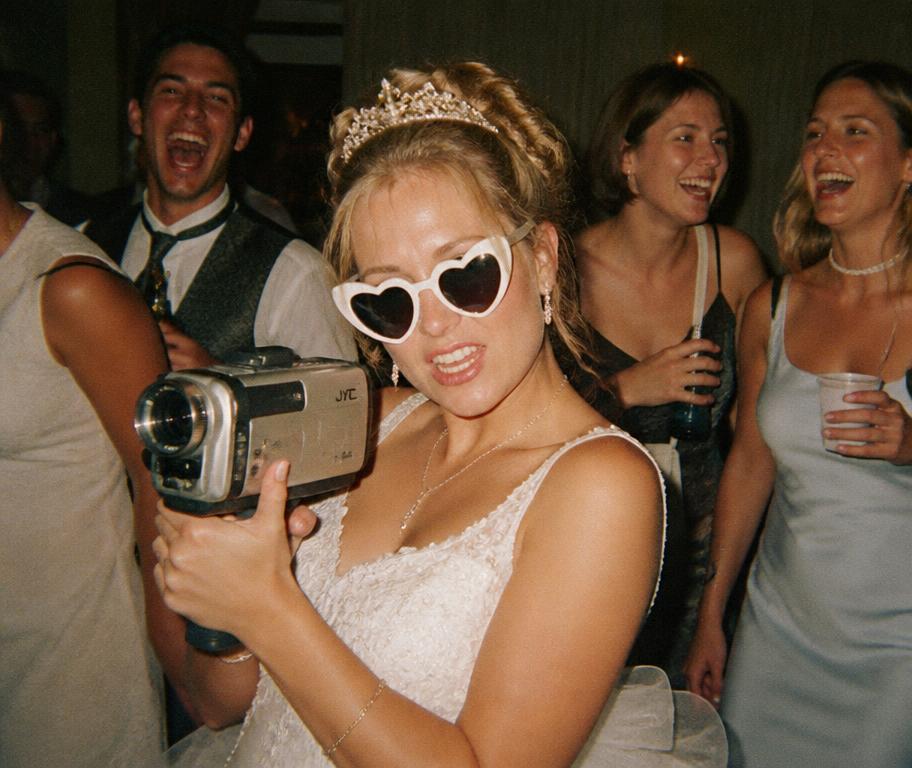Bride holding a vintage camcorder at the reception